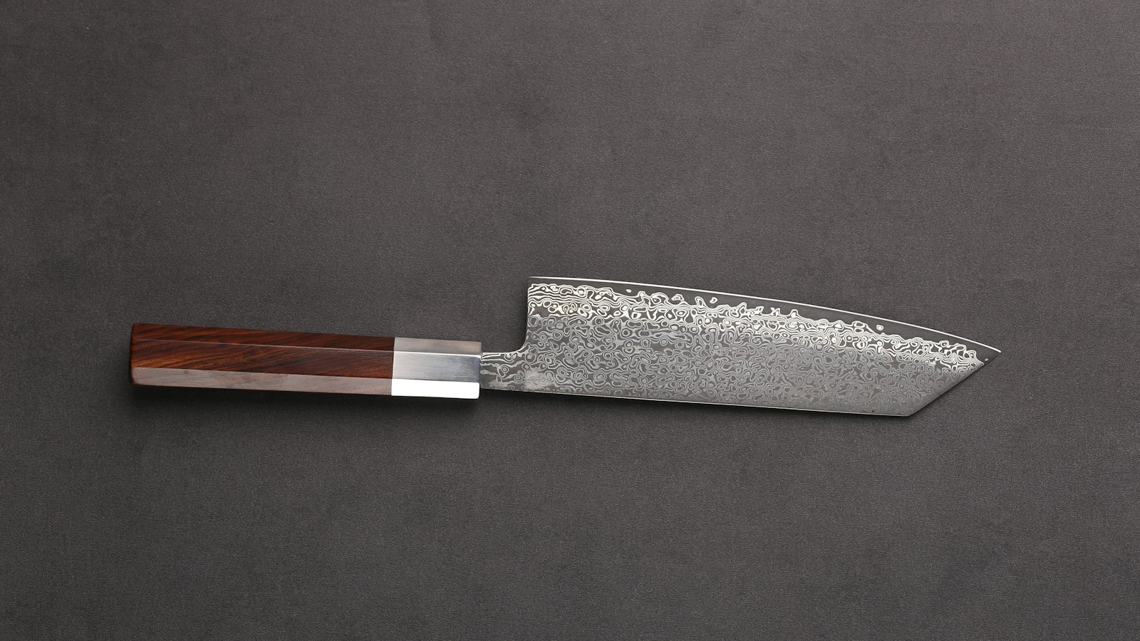 A Japanese chef knife with a wooden handle on a dark background