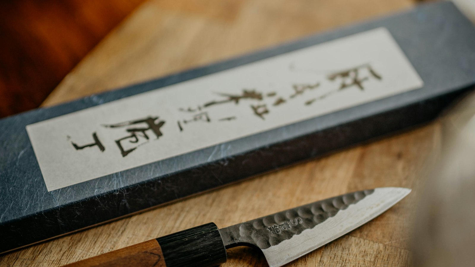 A Japanese knife beside its paper box with handwritten Japanese lettering